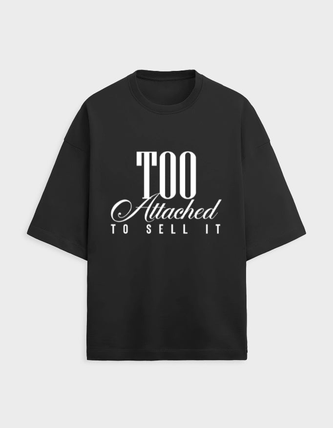 Black t-shirt with white text 'Too Attached To Sell It' on a light gray background