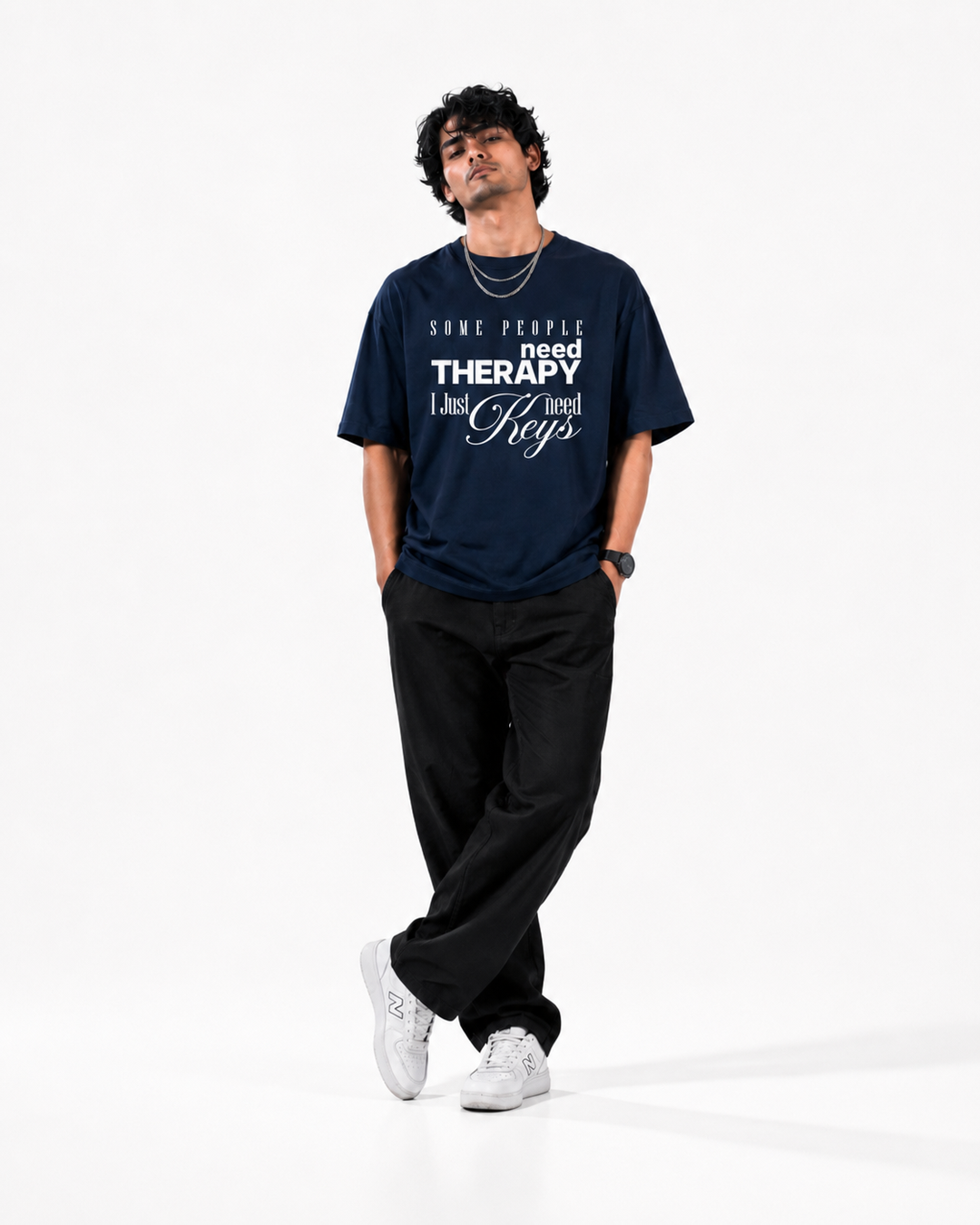 A man modeling a navy blue graphic t-shirt with white text that reads 'SOME PEOPLE need THERAPY I just need Keys', paired with black sweatpants and white sneakers, against a plain white studio background.